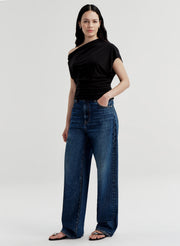Woman wearing a black top and blue jeans on a white background