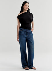 Woman wearing a black off-shoulder top and blue jeans on a white background