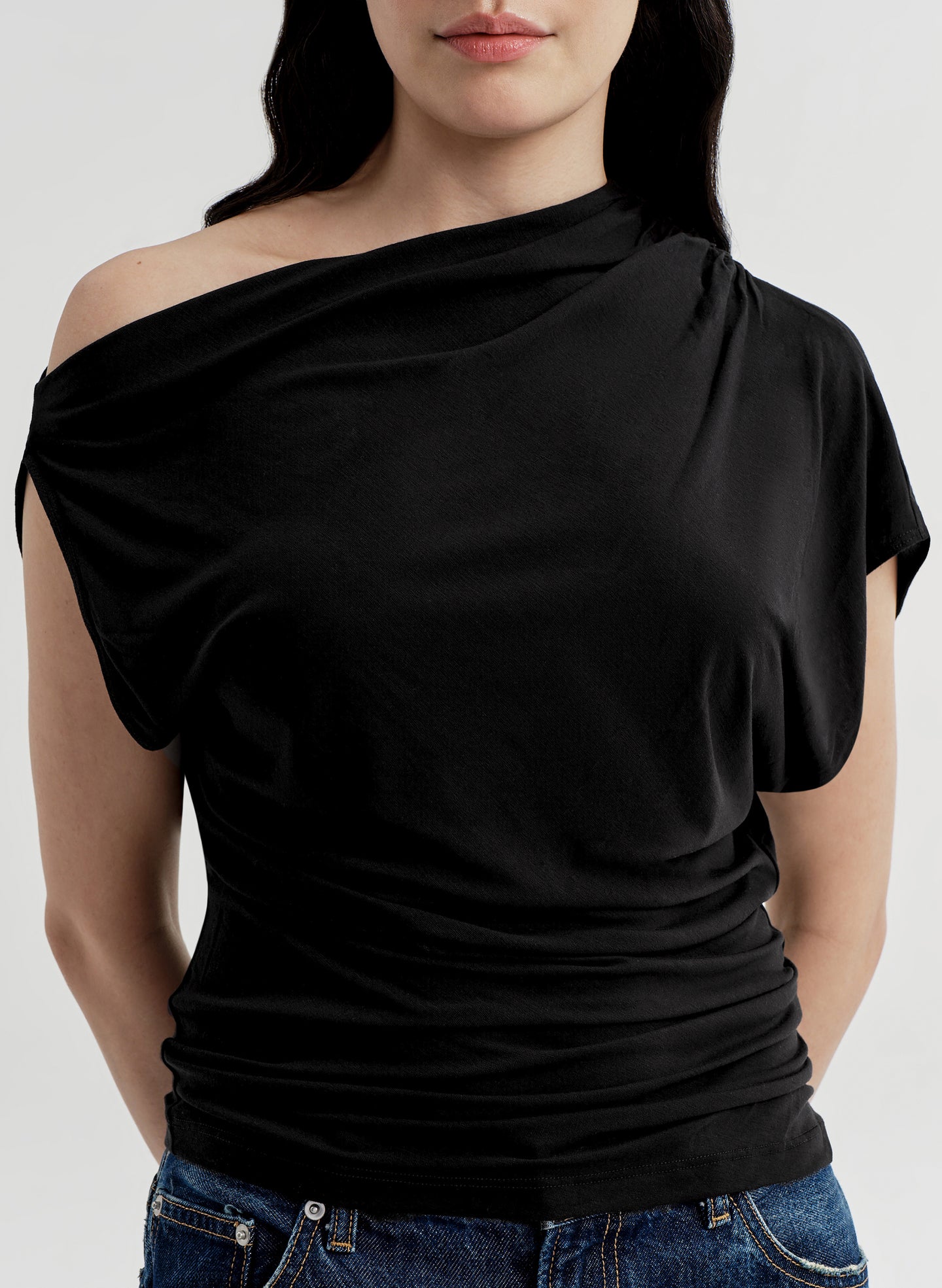 Black off-shoulder top worn by a person on a white background