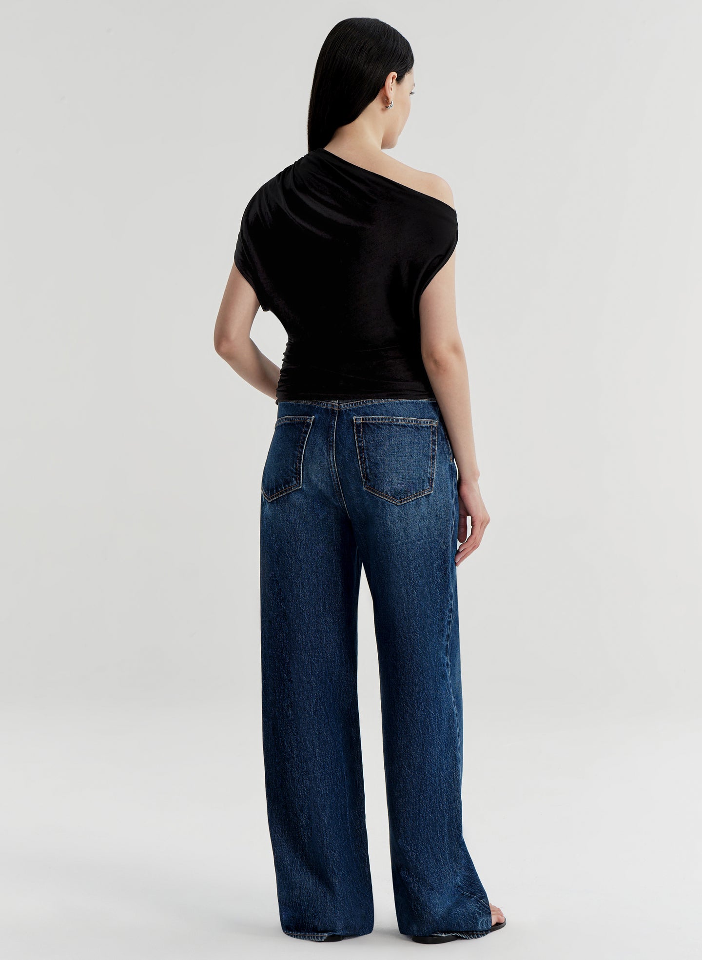Woman wearing blue jeans and a black top on a white background