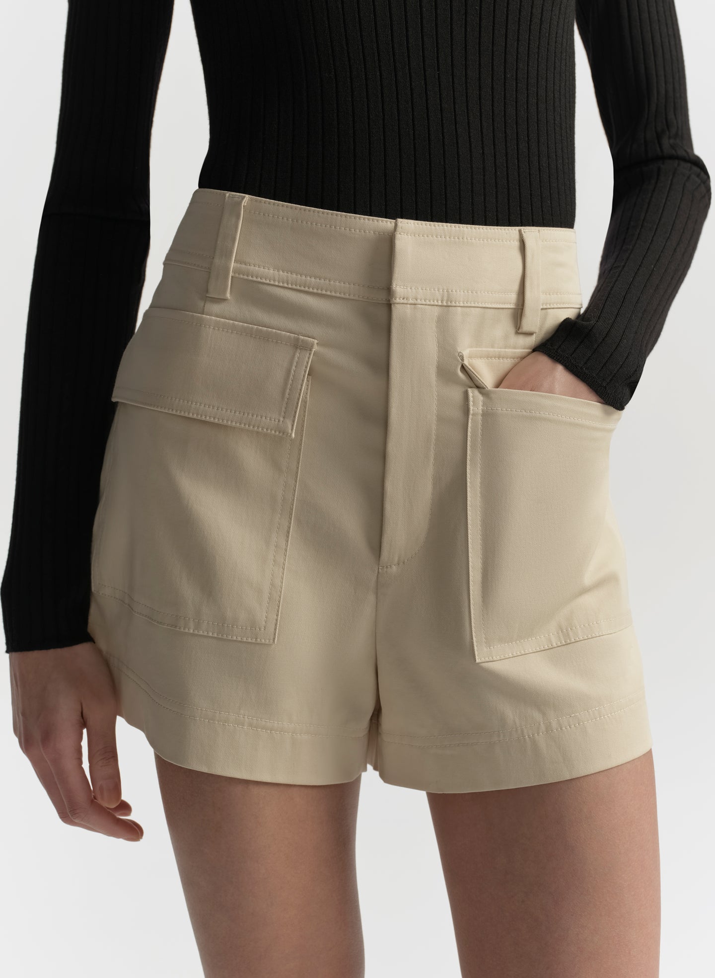 Beige shorts worn by a person with a black top on a white background