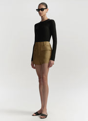 Person wearing a black long-sleeve top and hazel shorts on a white background