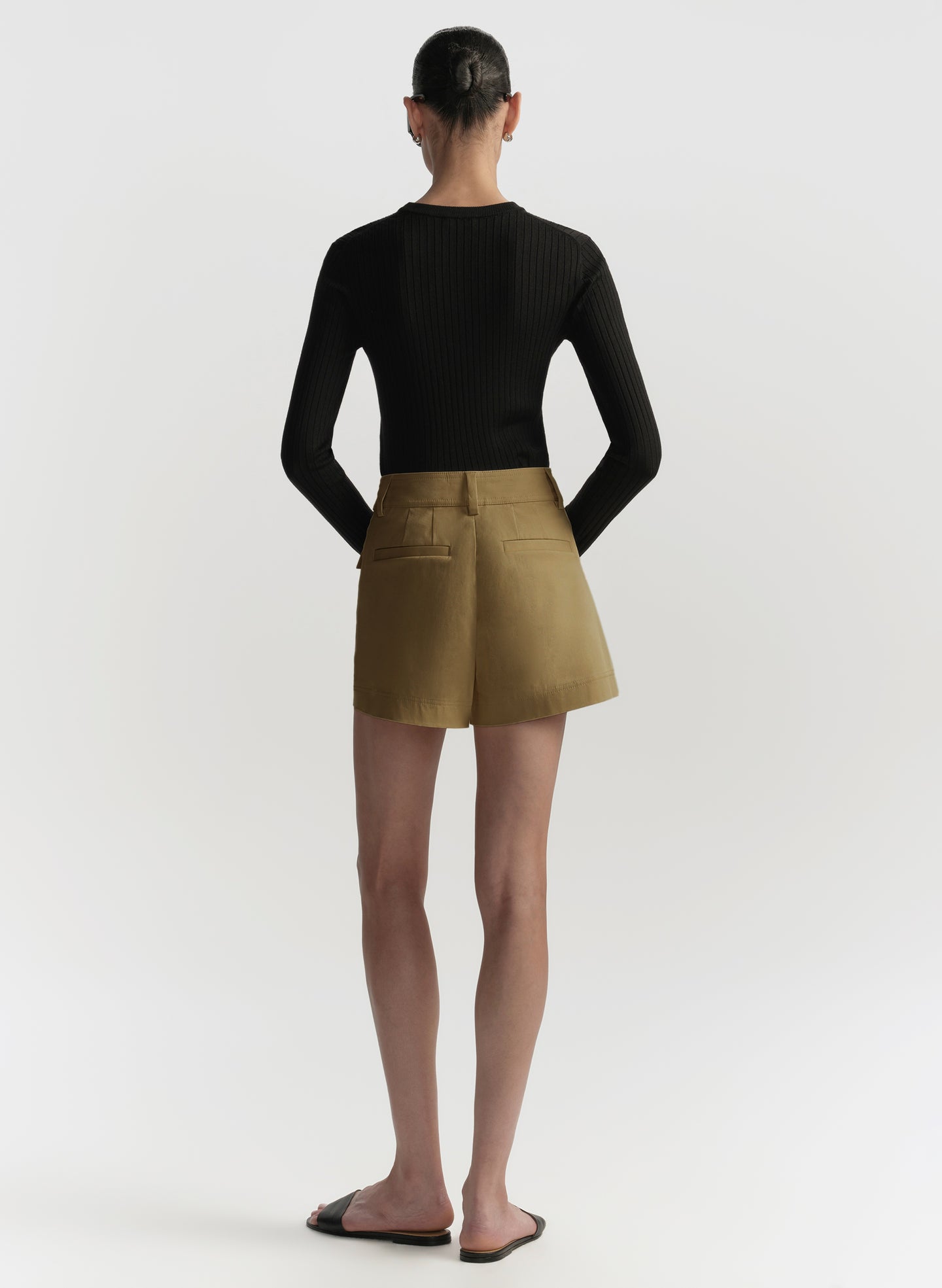 Person wearing a black top and brown shorts on a white background