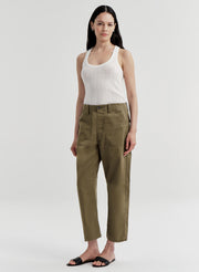 Woman wearing a white tank top and green pants on a white background