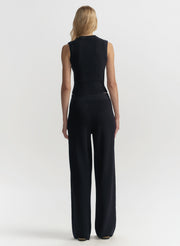 Woman wearing a blue sleeveless top and wide-leg pants on a white background