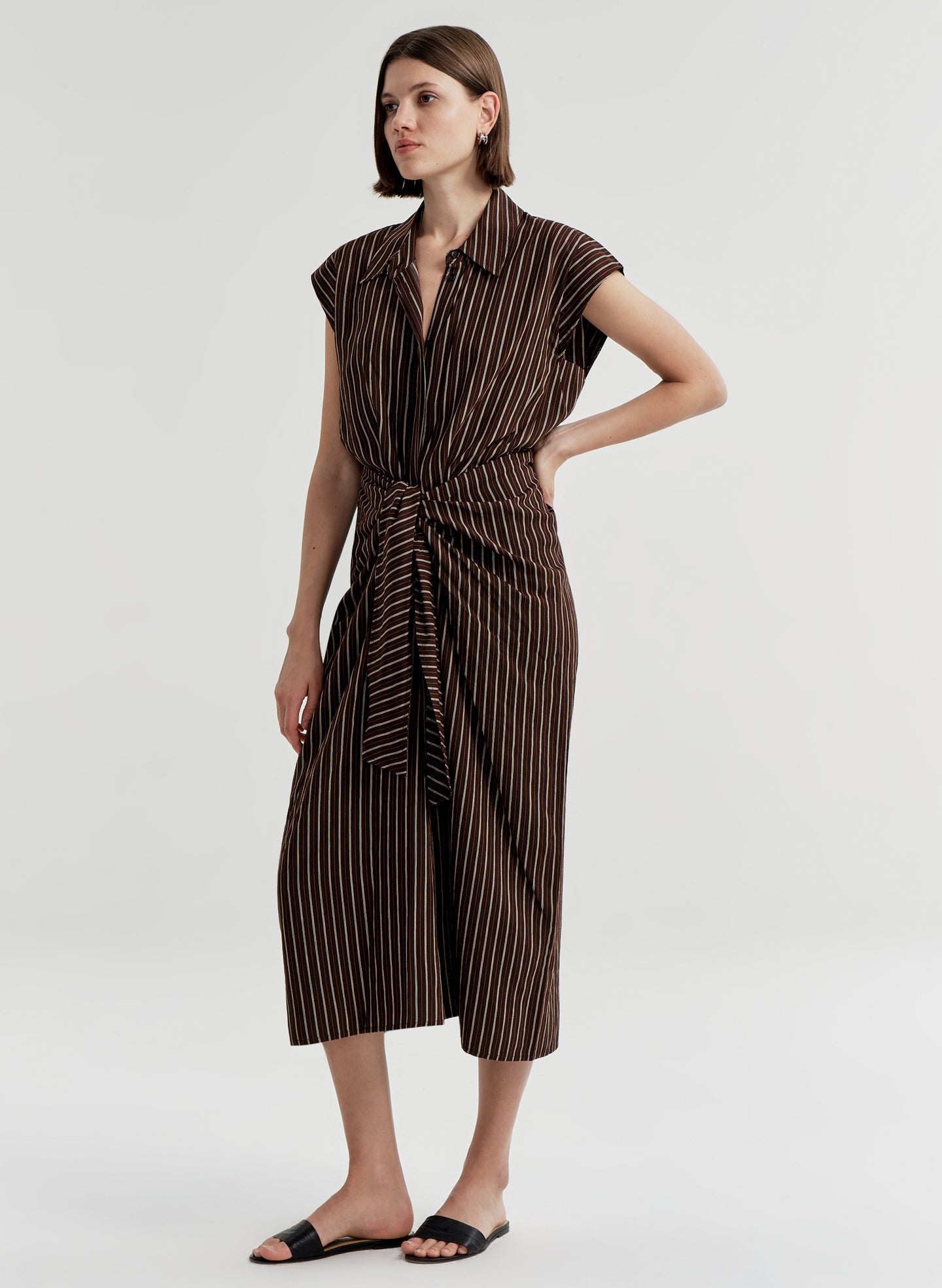 Woman wearing a brown and black striped dress on a white background
