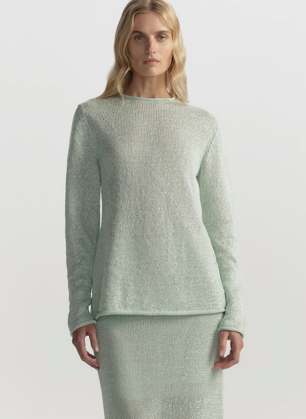 Woman wearing a light green sweater and skirt set on a white background
