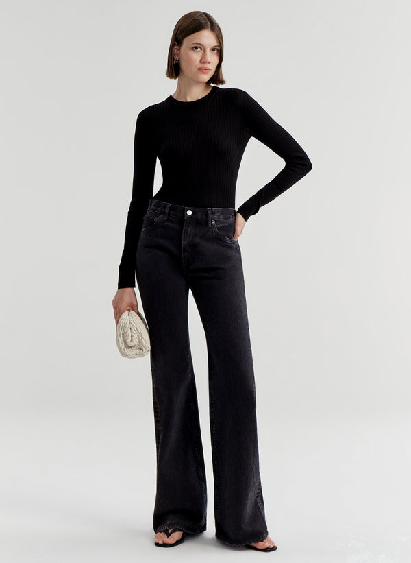 Woman wearing a black long-sleeve top and black jeans on a white background