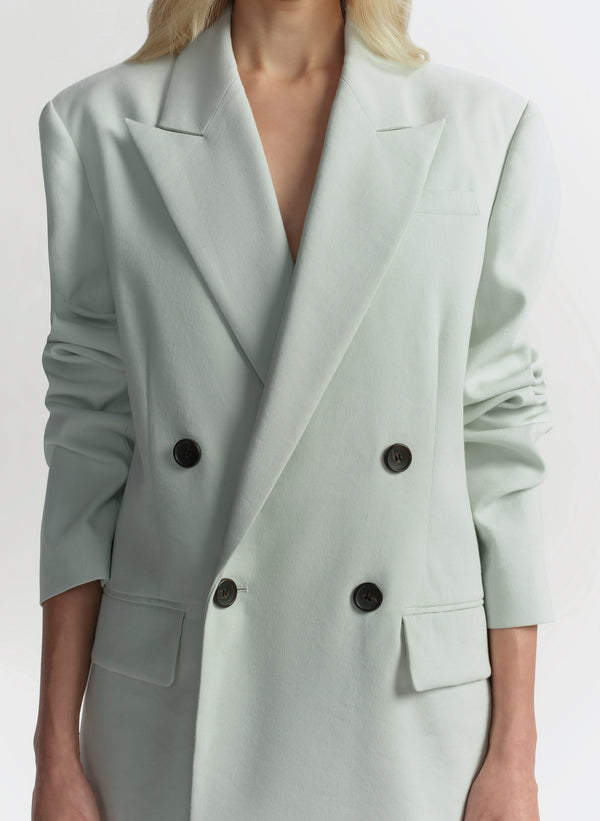 Light green blazer with black buttons on a white background
