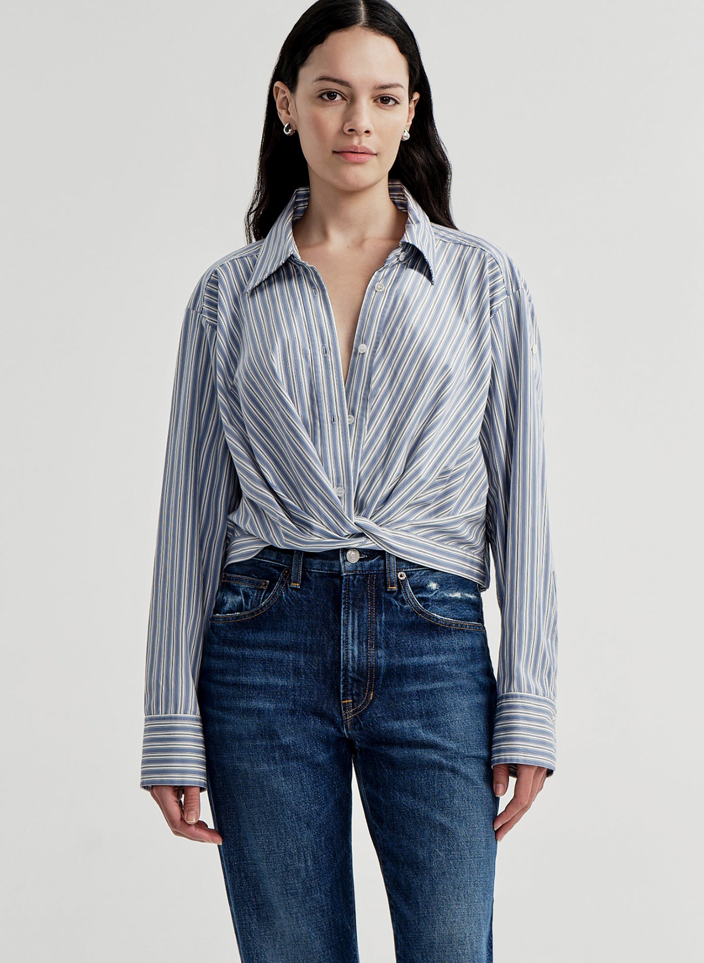 Woman wearing a striped shirt and jeans on a plain background