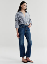 Woman wearing a striped shirt and blue jeans on a white background