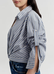 Person wearing a blue and white striped shirt with a plain background