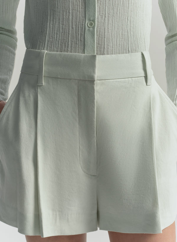 Light green shorts worn with a matching shirt on a plain background