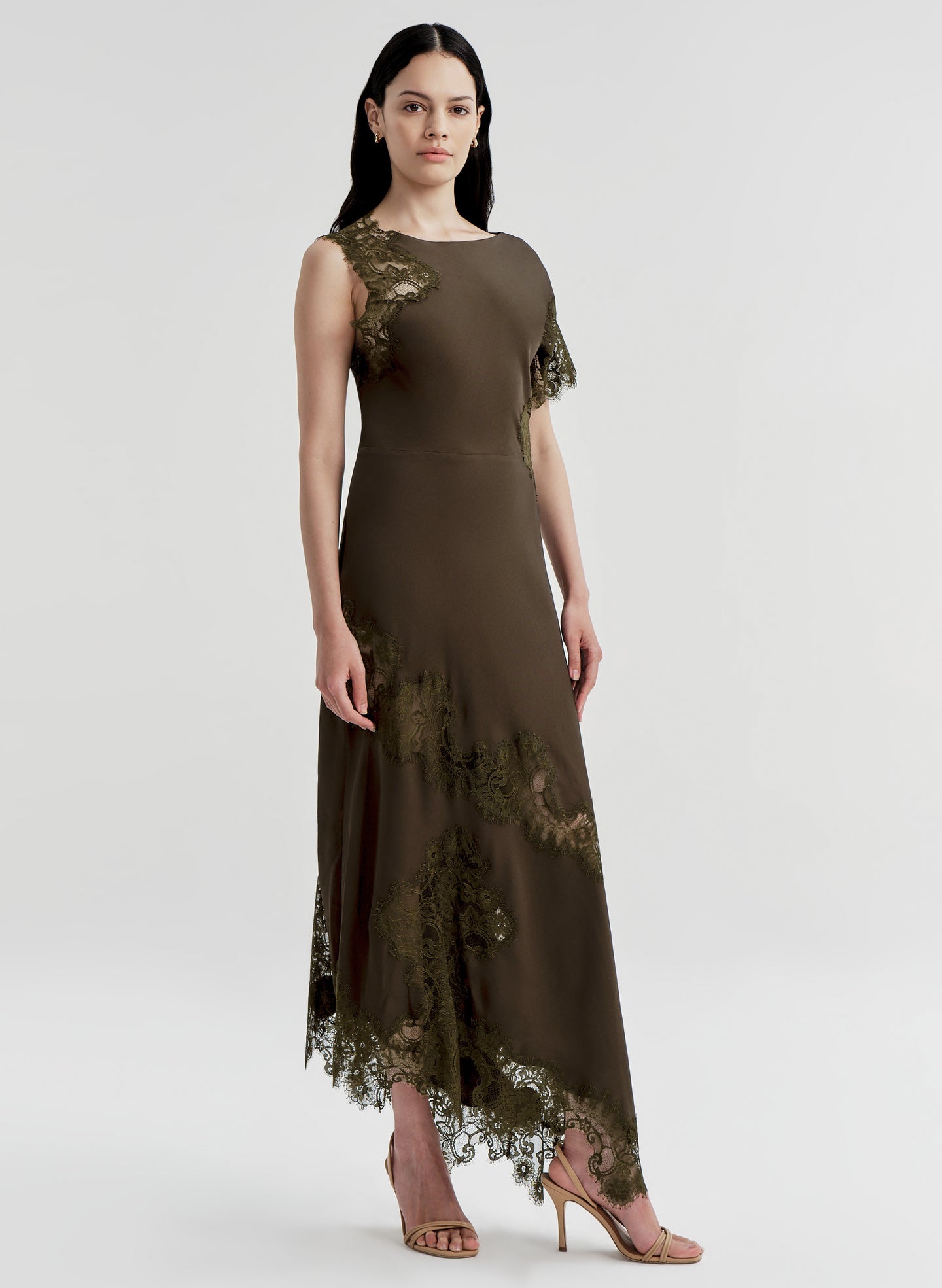 Woman wearing a long brown dress with lace details on a white background