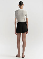 Person wearing a white ribbed top and black shorts on a white background