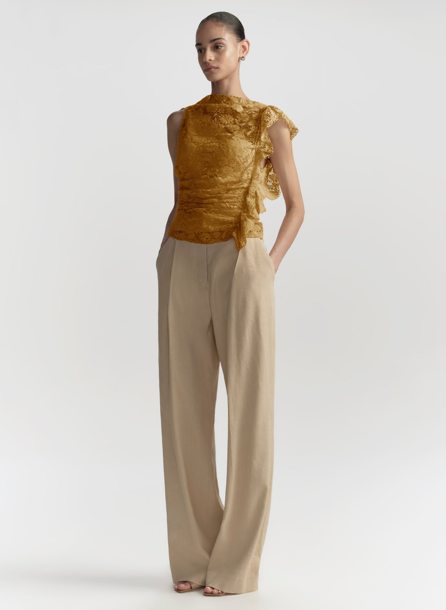 woman in gold lace top and beige pants