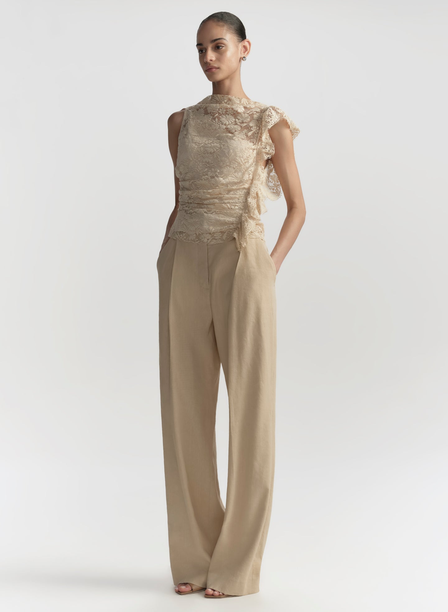 Woman wearing a beige outfit with a textured top and wide-leg pants on a white background