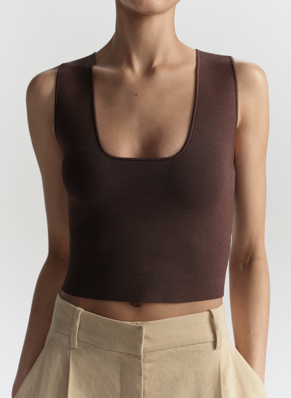 Woman wearing a brown tank top against a white background