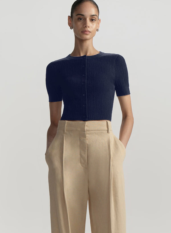 woman wearing cropped short sleeve cardigan in navy blue with tan pants