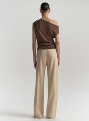 Woman wearing a brown off-shoulder top and beige pants on a white background