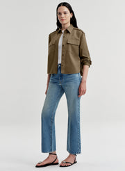 Woman wearing a brown jacket and blue jeans on a white background