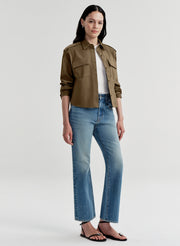 Woman wearing a green jacket and blue jeans on a white background