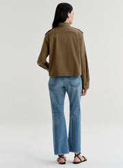 Person wearing a brown jacket and blue jeans on a white background