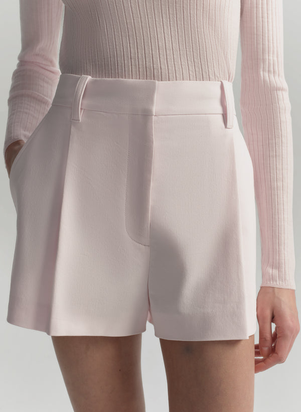 Light pink shorts worn with a matching top on a neutral background