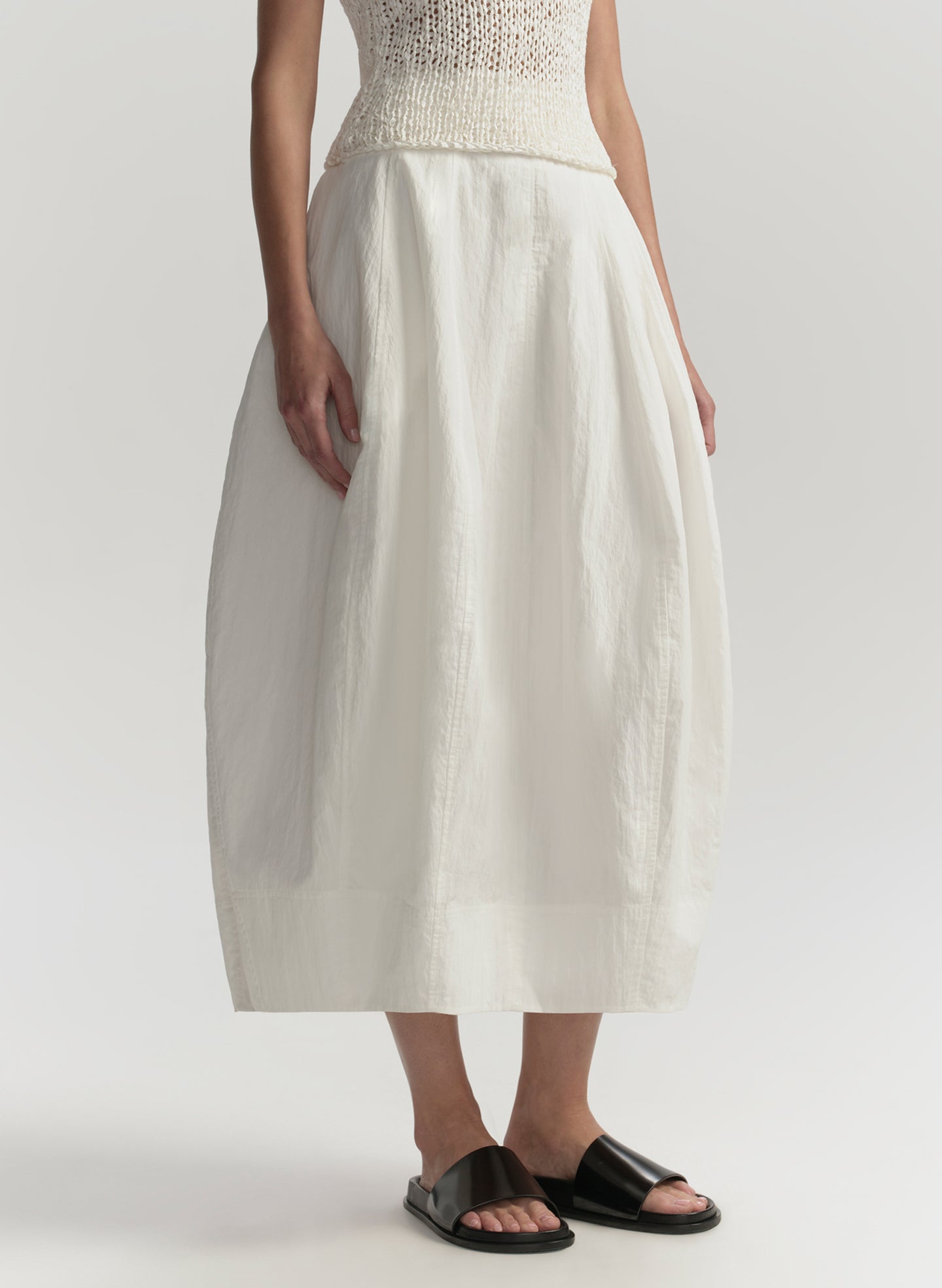 Person wearing a white skirt and top on a plain background