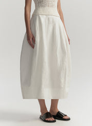 Person wearing a white skirt and top on a plain background