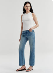 Woman wearing a white sleeveless top and blue jeans on a white background