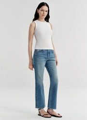 Woman wearing a white sleeveless top and blue jeans on a white background