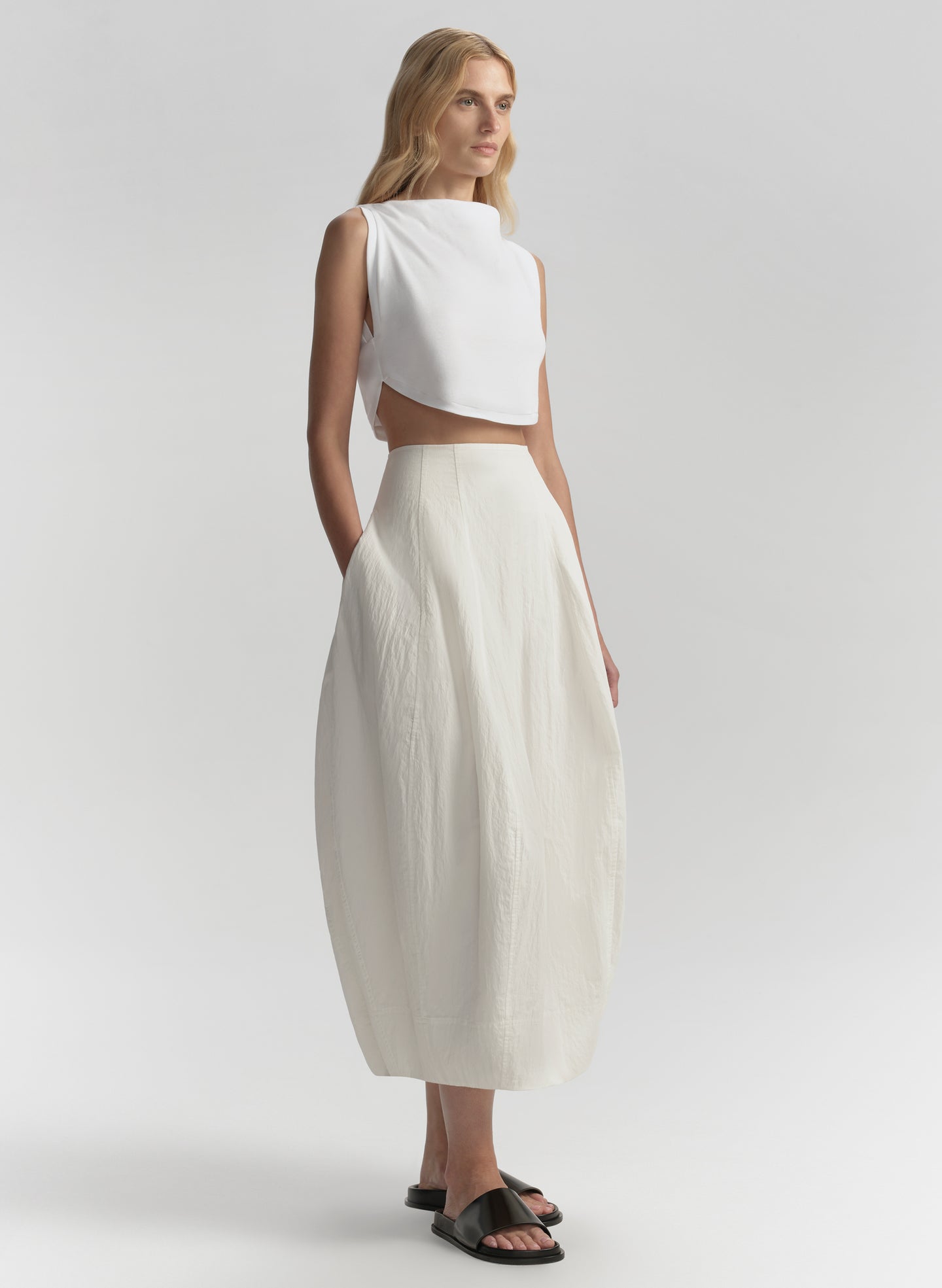 woman wearing white sleeveless top and matching skirt