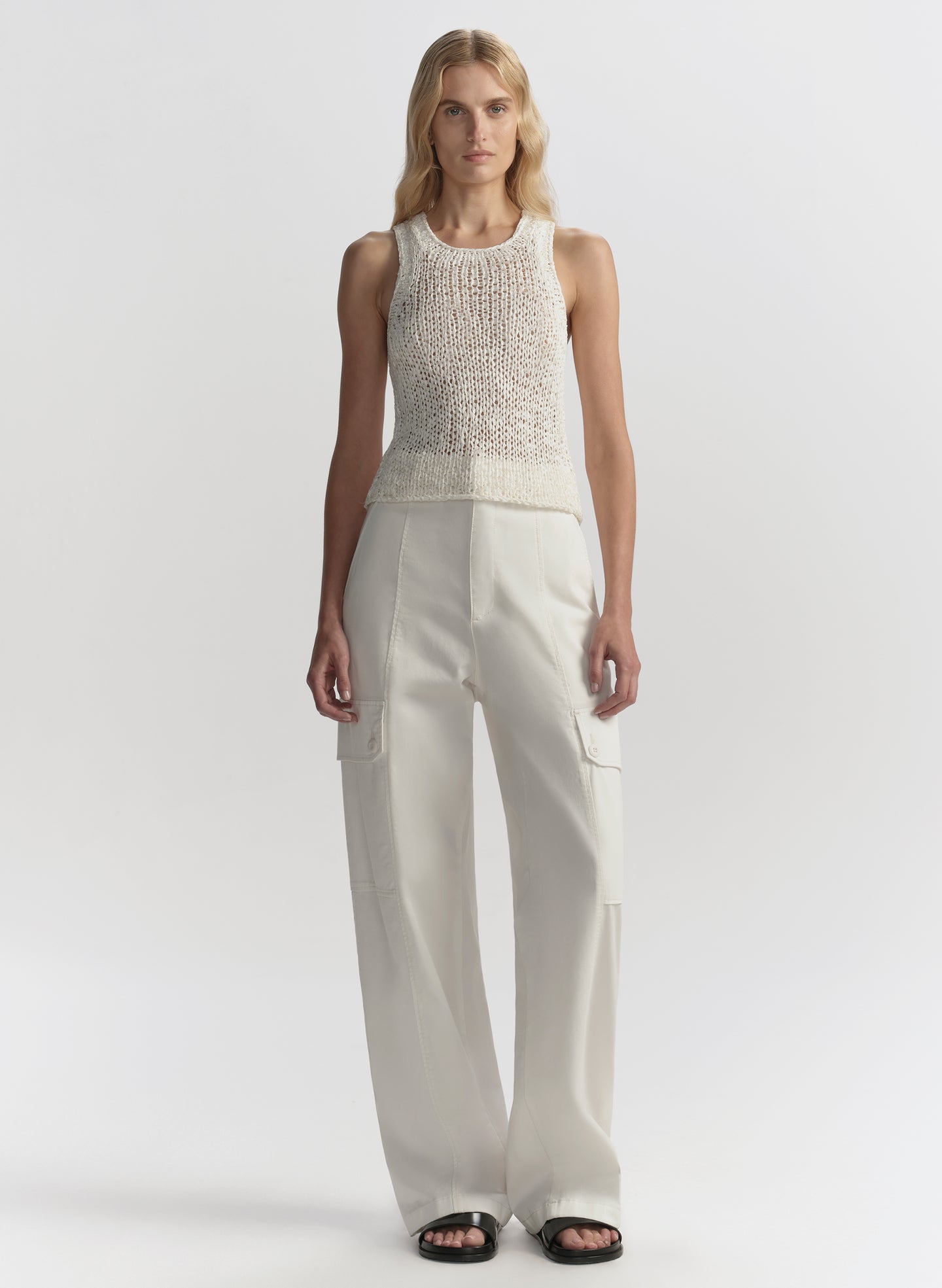 Woman wearing a white sleeveless top and pants on a white background