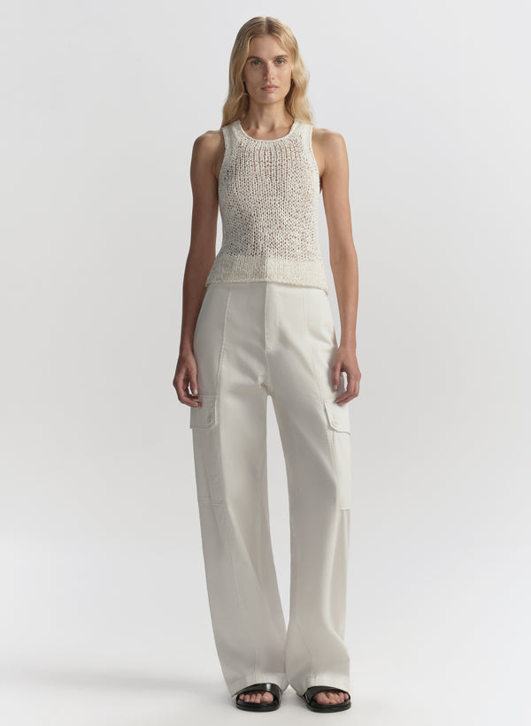 Woman wearing a white sleeveless top and pants on a white background