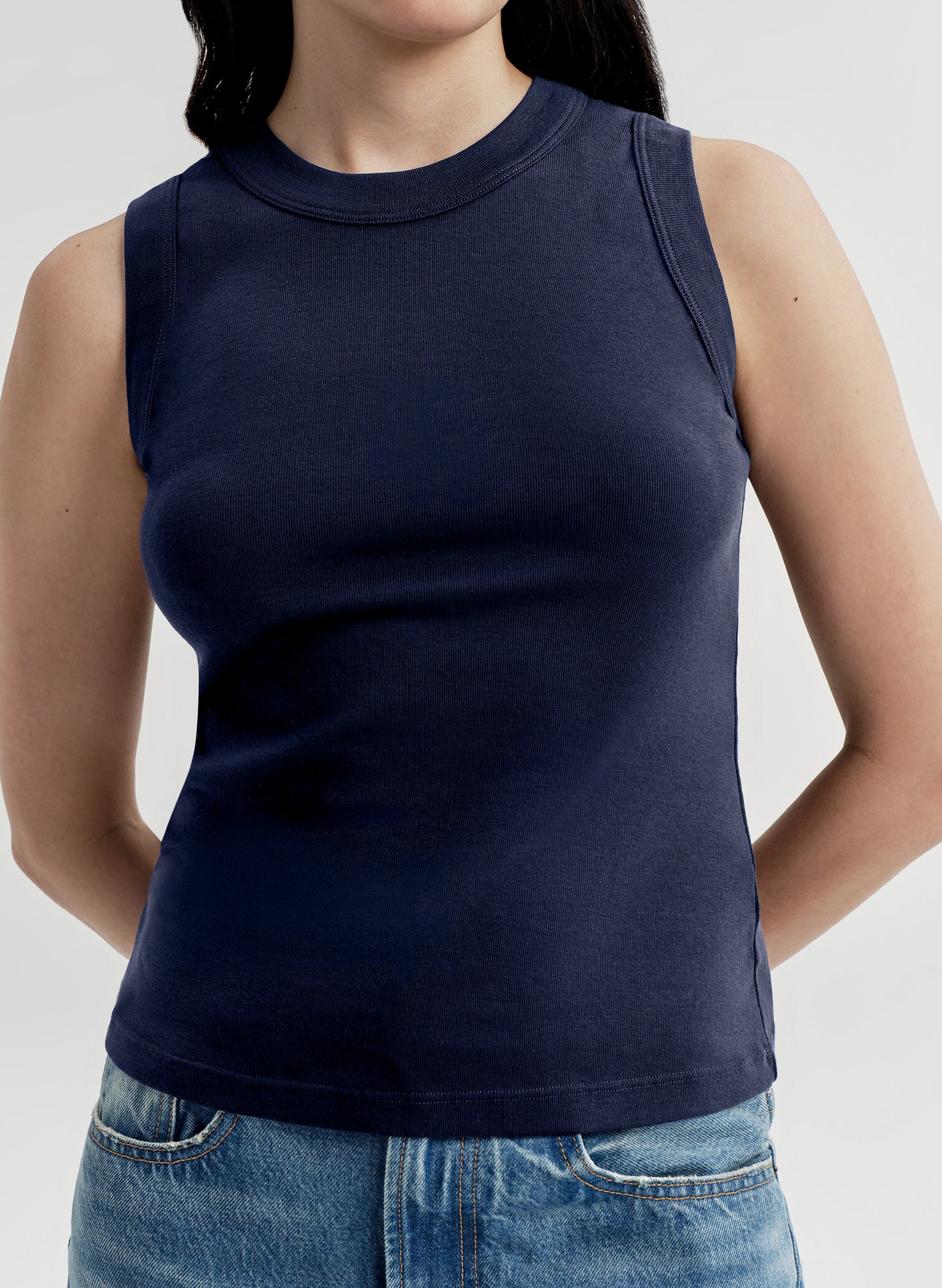 Person wearing a navy blue sleeveless top against a white background