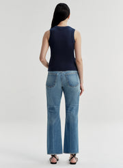 Woman wearing a navy sleeveless top and blue jeans on a white background