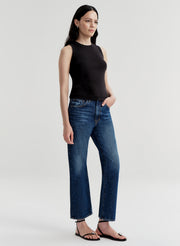 Woman wearing a black sleeveless top and blue jeans on a white background