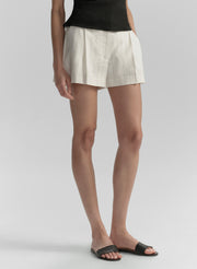 Person wearing white shorts and black sandals on a plain background
