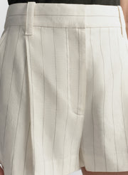 Close-up of beige pleated shorts with a focus on the fabric texture.
