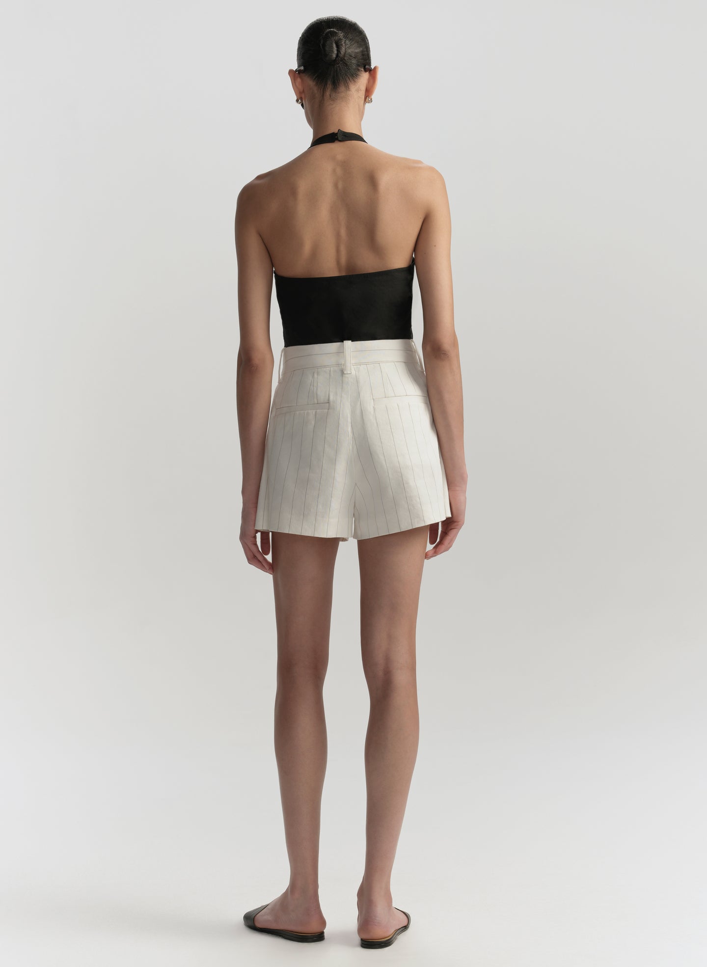 Person wearing a black top and white shorts on a plain background