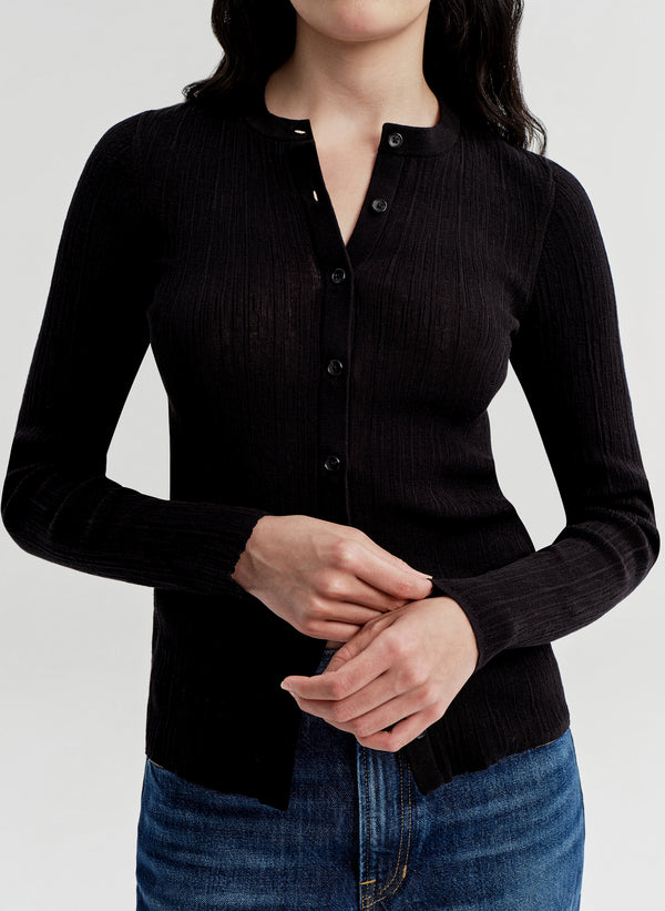 Person wearing a black long-sleeve shirt with a plain background