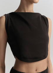 Black sleeveless top worn by a model on a plain background
