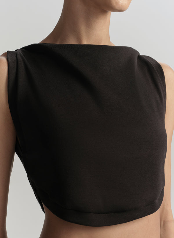 Black sleeveless top worn by a person on a light gray background