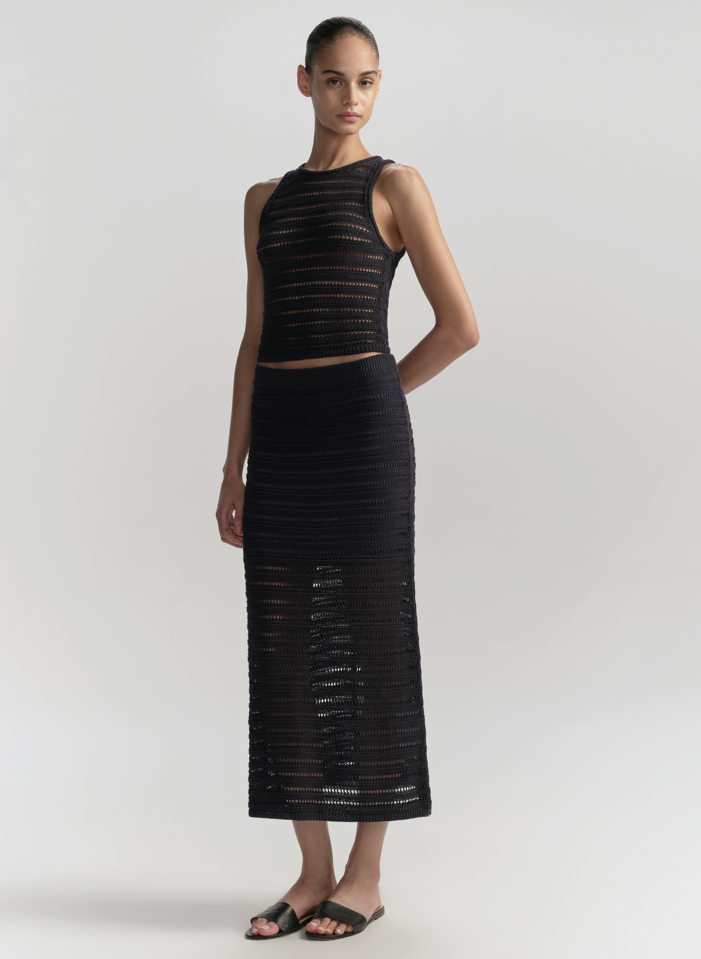 Woman wearing a blue sleeveless top and skirt set on a light gray background