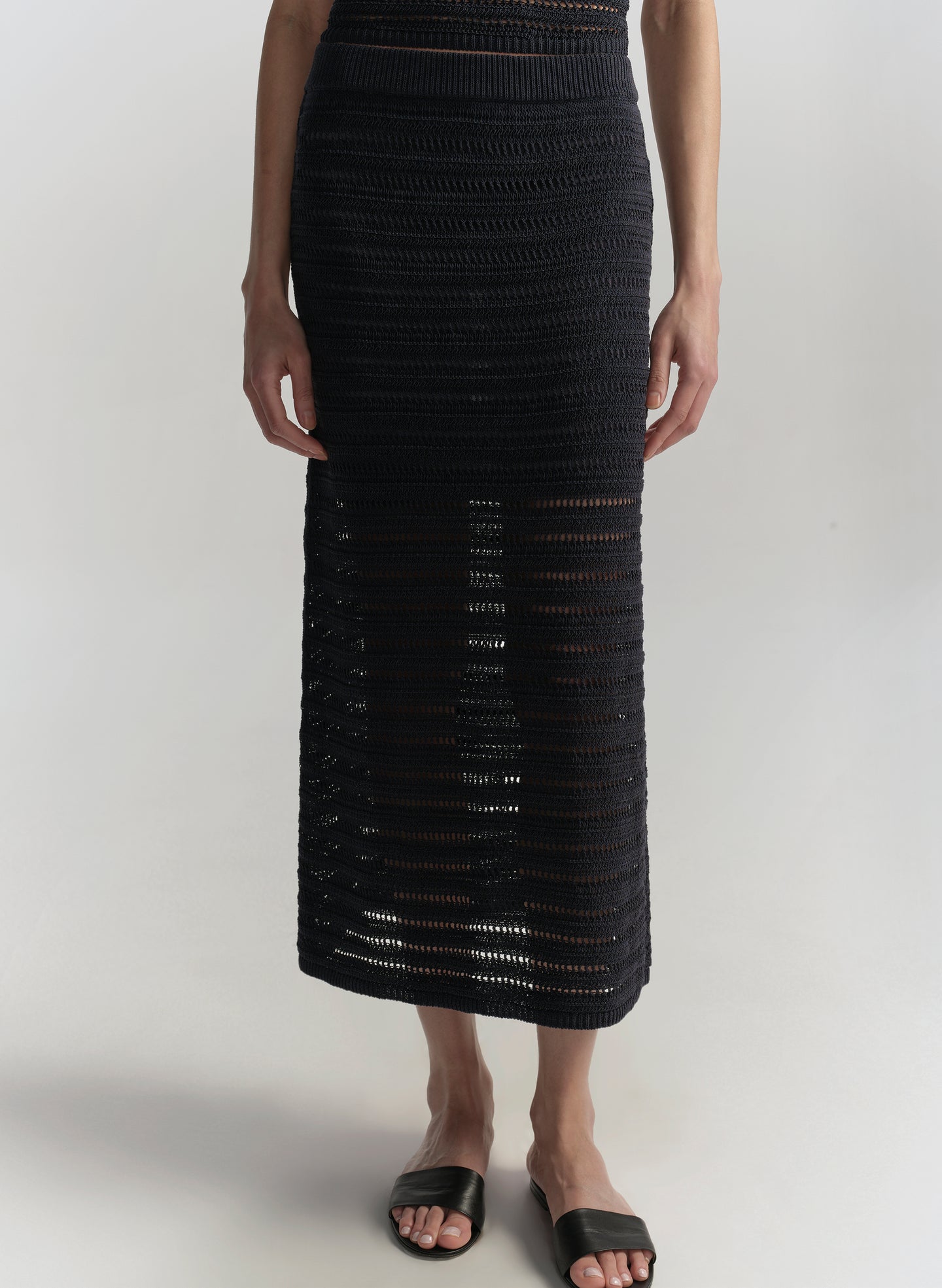 Person wearing a blue crochet skirt on a white background