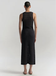 Woman wearing a bllue sleeveless top with skirt with textured pattern on a white background