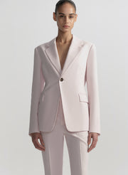 Woman wearing a light pink suit on a plain background