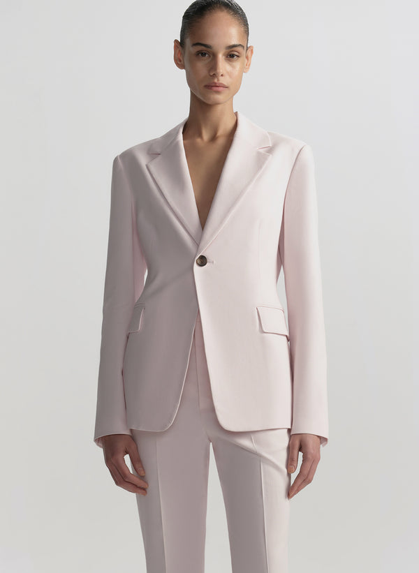 Woman wearing a light pink suit on a plain background