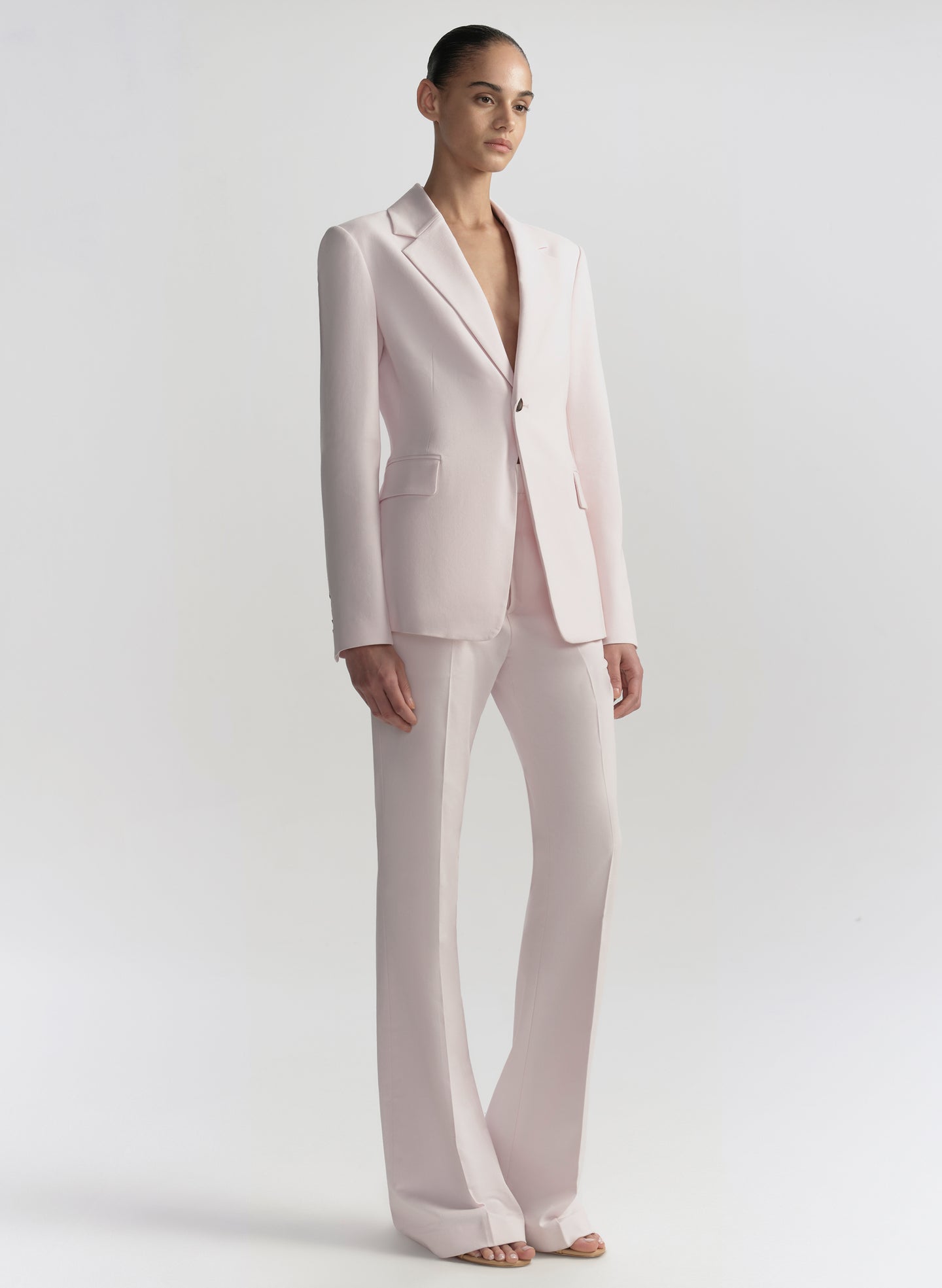 Woman wearing a light pink suit on a plain background